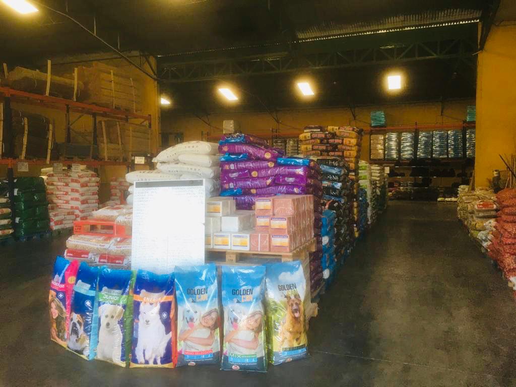 Pasillo de almacén con productos para mascotas y suministros agrícolas.