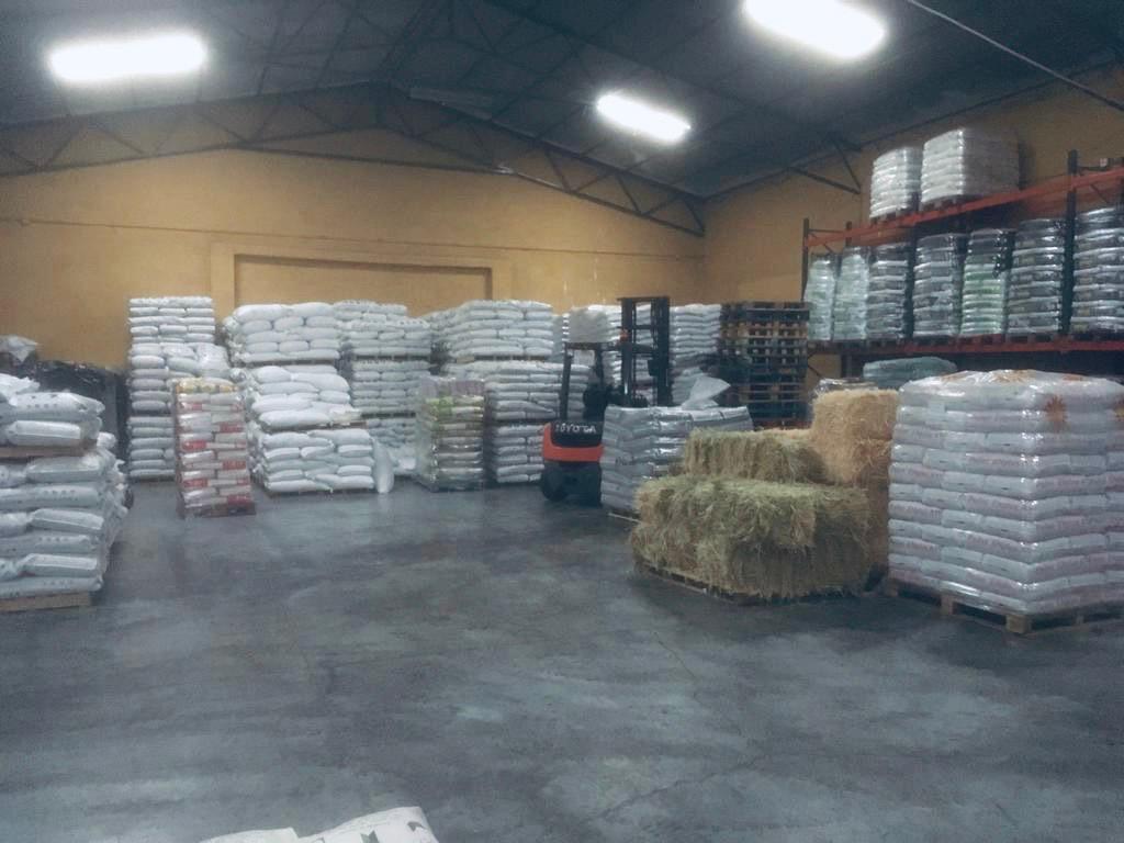 Pasillo de almacén con productos agrícolas y para mascotas.